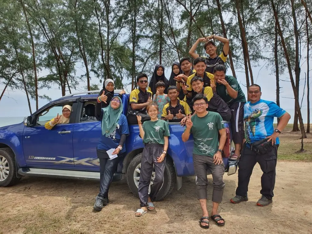 Photograph of volunteers posing in front of a blue truck